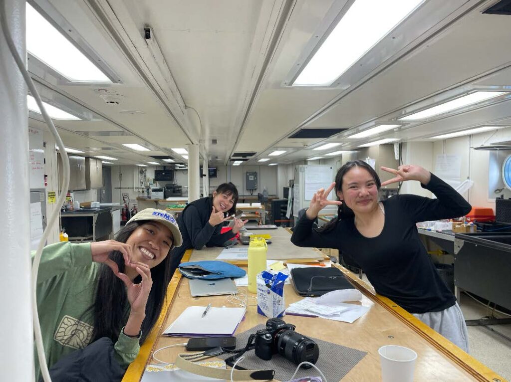 Three happy scientists pose around a big work bench