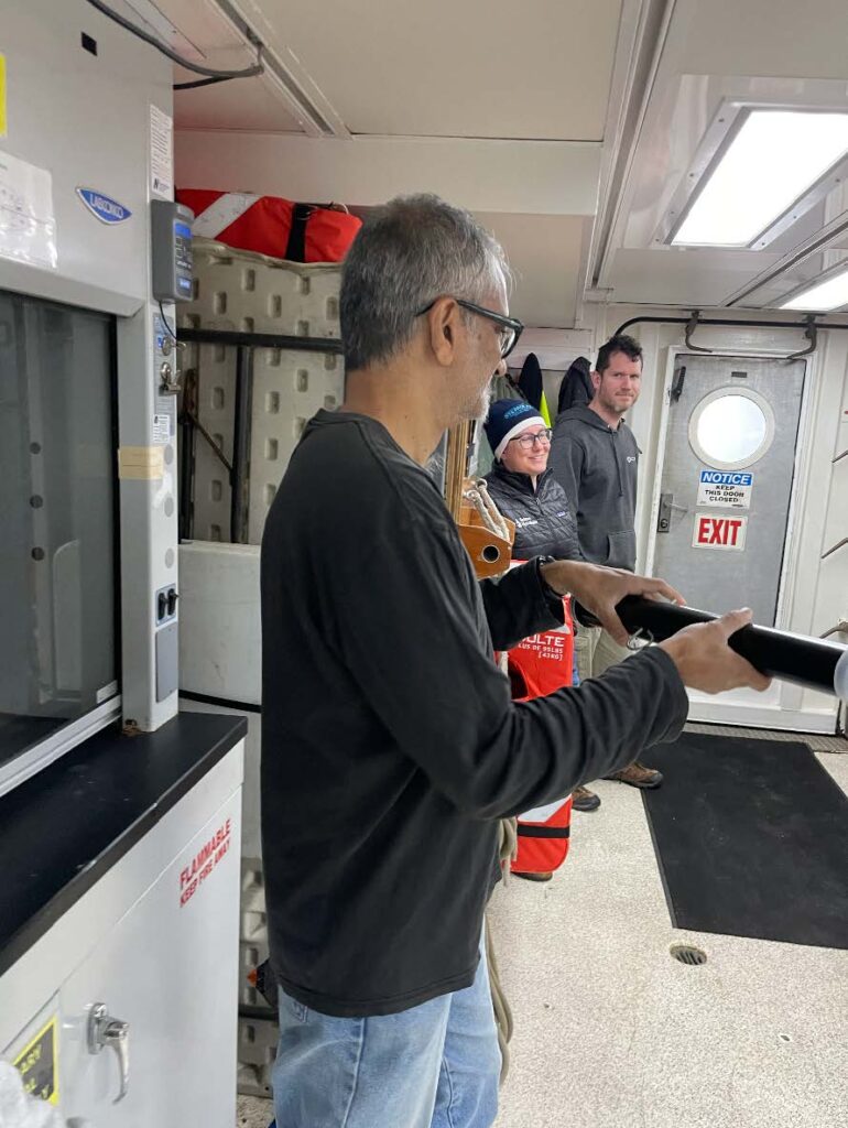 A scientist holds an instrument that looks like a black pipe