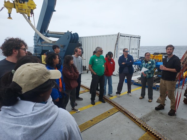 A group of scientists stands on the deck of a ship