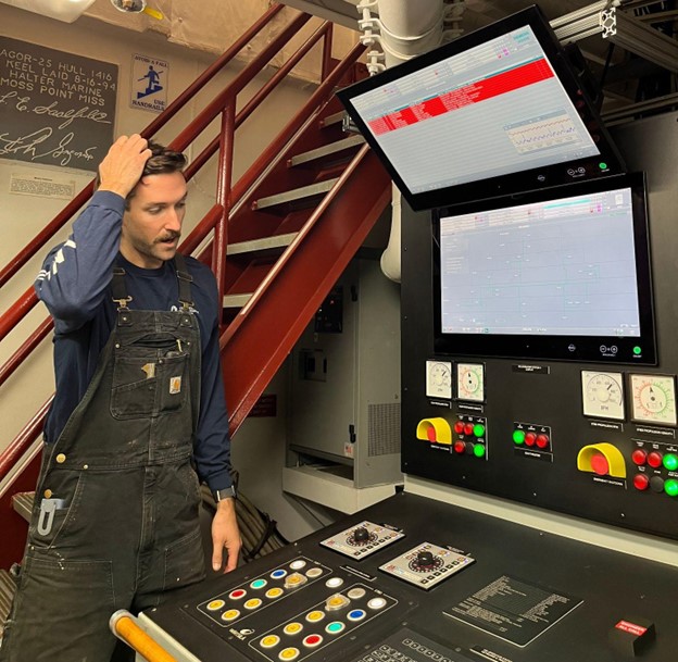 Engineer scratching his head and looking at a control panel