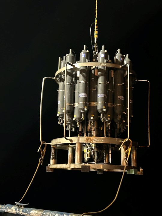 An instrument with a metal frame and grey bottles is suspended in the night sky