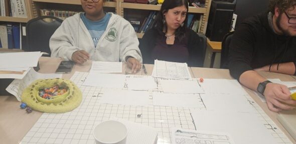 Two people sit at a table covered with papers to play Dungeons and Dragons
