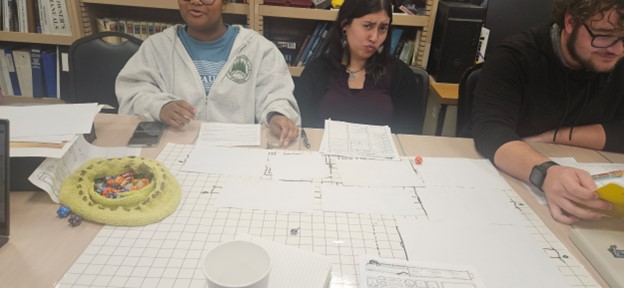 Two people sit at a table covered with papers to play Dungeons and Dragons