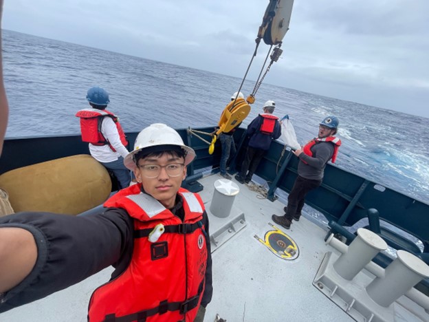 Scientist with hard hats and red life vests deploy a plankton net off the ship