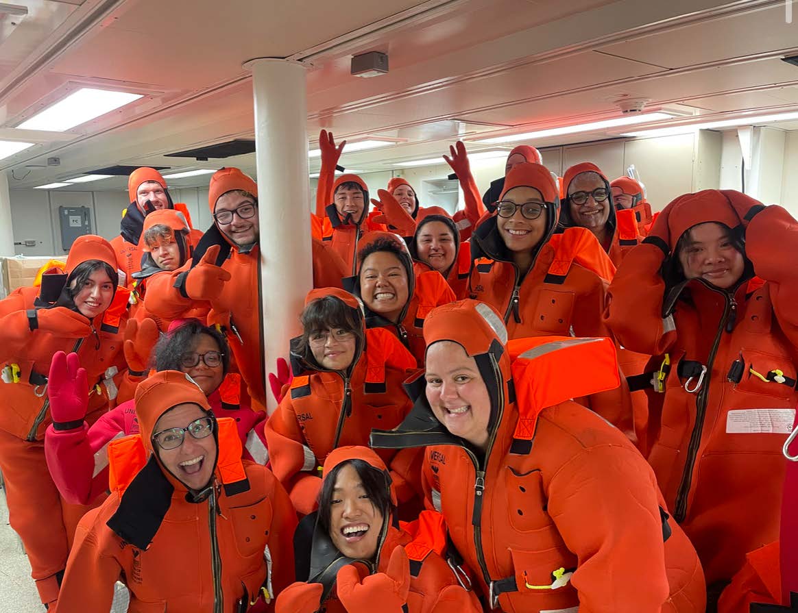 A group of scientists pose in bright red neoprene full-body immersion suits