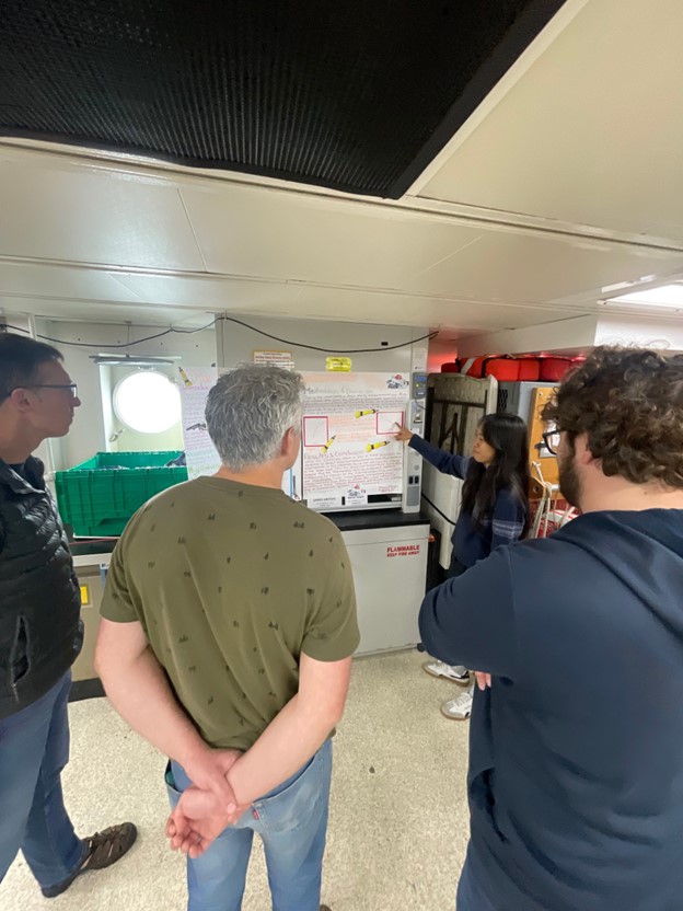 A student points at a scientific poster with three onlookers