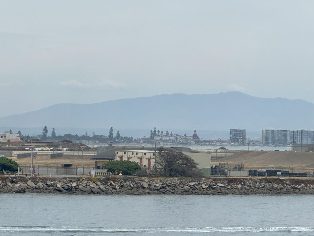 View from Atlantis in port shows a beige building and Coronado Island in the background