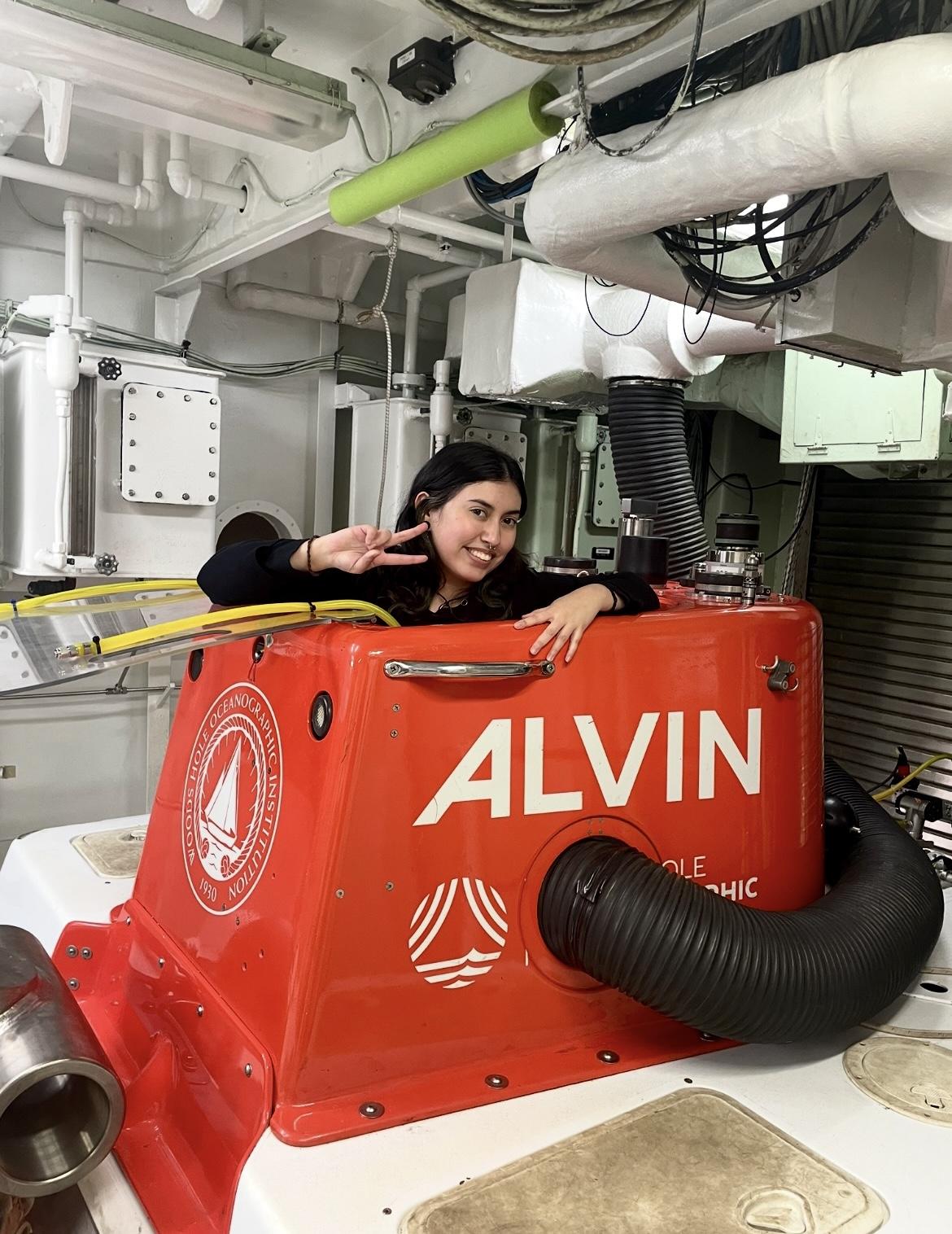 A scientist poses with a smile out the top of Alvin's red cap