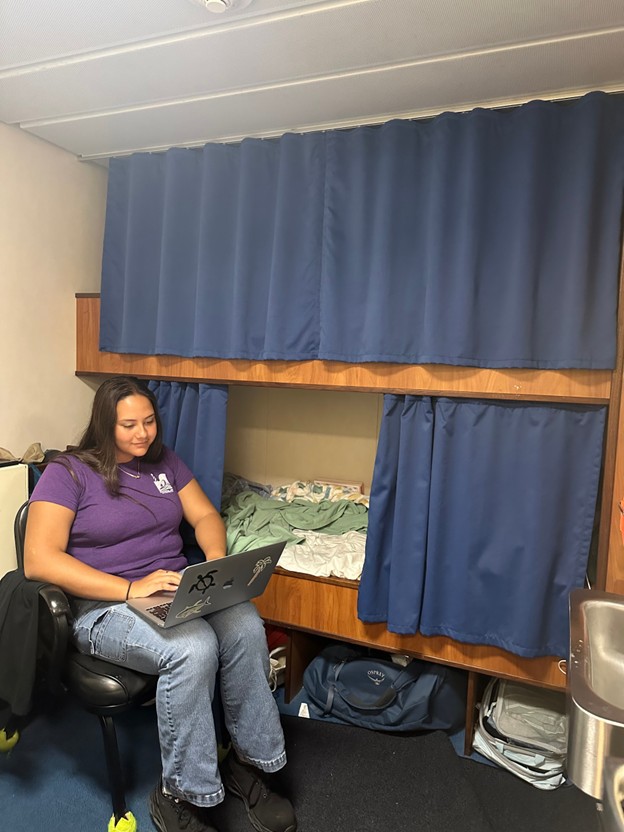 student sitting in one of the ship's bunks 