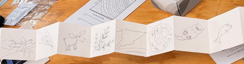 Lisa's book with a plane, a pizza, a moose, a plant, a glacier, the R/V Sally Ride bloat, an otter, and dolphin drawn across the pages