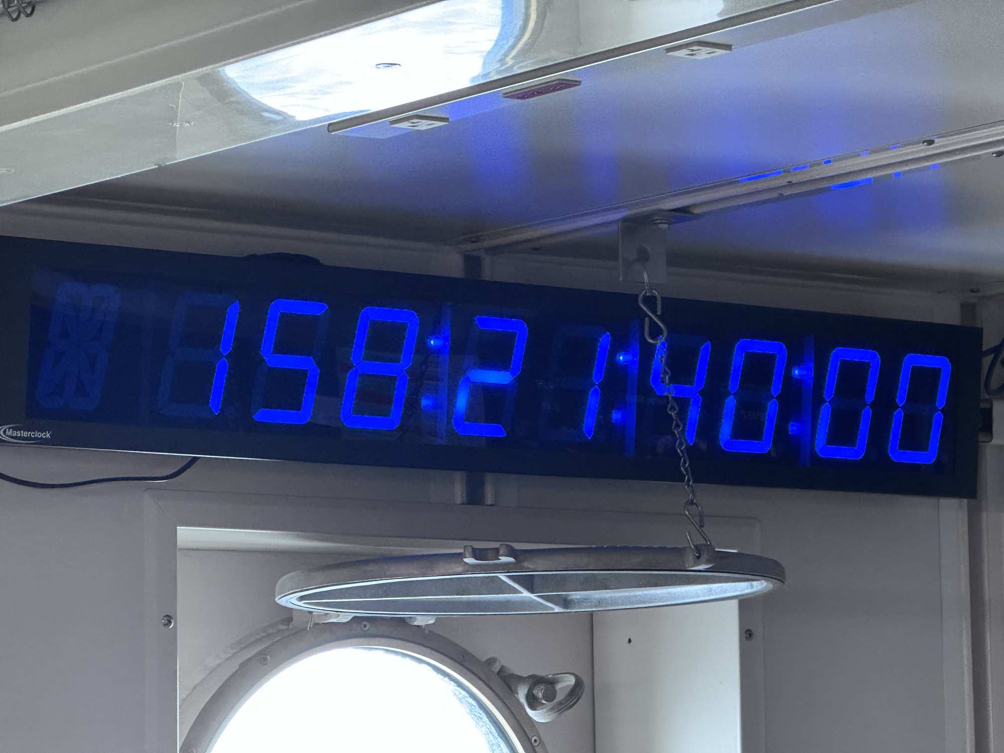 Clock says 158:21:40:00 on it. Clock is over a porthole on the vessel.